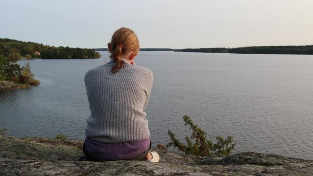 Thoughtful girl looking at the Swedish Mälaren lake. Freedom and leisure concept. Stockholm, Sweden.