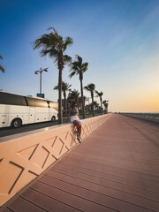 Dubai, UAE. September 27, 2023: a cute girl sits on a fence in shorts and a white tourist bus...
