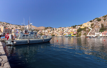 Fototapeta na wymiar Colorful houses on the slopes of the mountains on the island of Symi on a bright sunny day.