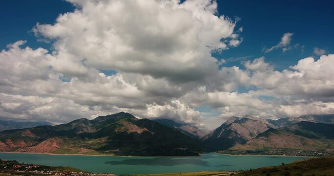 Mountain landscape timelapse video for background. Fluffy soft clouds over a turquoise lake or reservoir in the Charvak mountains. Time lapse clouds moving fast. Concept of freedom and calmness