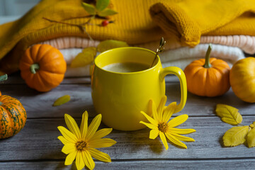 Autumn, autumn leaves, a hot steaming cup of coffee and a warm sweater on the background of a wooden table. Seasonal, morning coffee, Sunday relaxation and still life concept.
