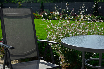 metalowy fotel i szklany stolik w ogrodzie, kącik wypoczynkowy, metal armchair and glass table in...