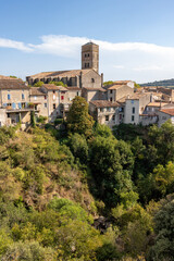 Fototapeta na wymiar A view of the village of Montolieu Aude Languedoc - Roussillon France. Trees valley ancient houses and church bell tower. 