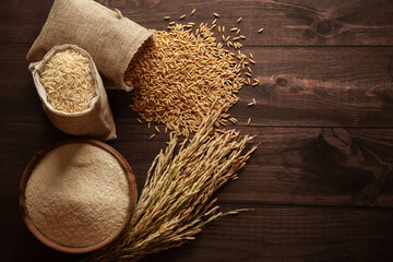 Top view of organic Rice (Oryza sativa) flour in a wooden bowl and raw stages of rice in a jute bag.