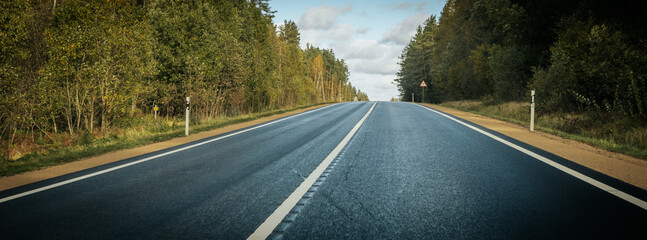 Riga - Valmiera asphalted new road. Road traffic on Latvian roads. Road with asphalt coating. Heavy and light vehicle movement. - obrazy, fototapety, plakaty