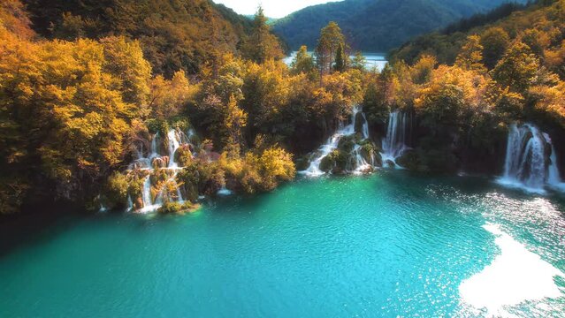 Golden autumn forest and mountain lake with amazing waterfalls. Clear emerald green water. Sunny weather quickly changes to dark.