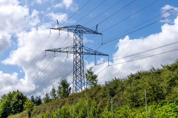 Electricity concept. Electricity concept. High voltage power line pylons, electrical tower on a green field with blue sky.