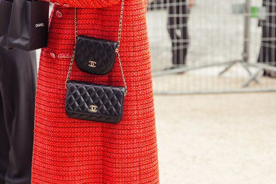 Closeup of black handbags, woman walking on the street wearing a red outfit - Chanel Paris Fashion Week Street Style