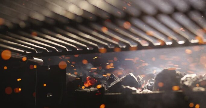 fanning hot coals for barbecue grill in the kitchen of the restaurant sparks fire slow motion, preparation for grilling party outdoors, hot content concept