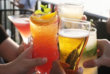 Friends toasting, saying cheers holding tropical blended fruit margaritas. Watermelon, beer and fresh orange drinks.	