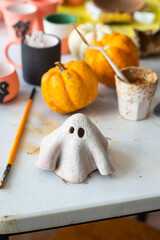 Table cluttered with various unfinished Halloween crafts at a ceramics, pottery studio with tools,...