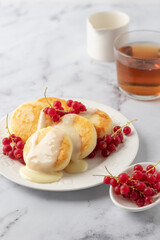Cottage cheese pancakes, syrniki, ricotta fritters with fresh berries and sour cream on white...