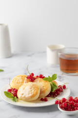 Cottage cheese pancakes, syrniki, ricotta fritters with fresh berries and sour cream on white marble background. Healthy and delicious breakfast, high key, text space