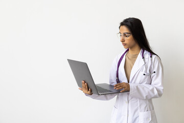 Cheerful young indian woman medical worker in uniform works at computer isolated on white background.