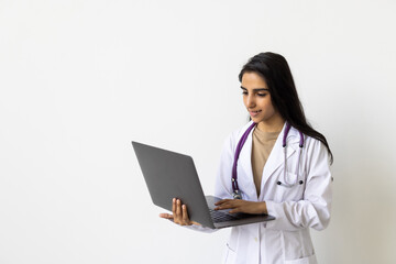 Cheerful young indian woman medical worker in uniform works at computer isolated on white background.