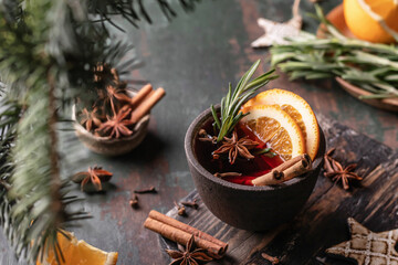 Mulled wine in ceramic mug with orange slices and spices. Christmas hot drink on wooden table with...