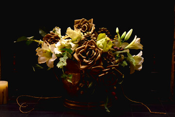 Close-up of a bouquet of roses, Lily, and other flowers in a vase on a black background.