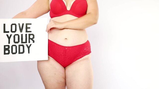 Portrait of self loving woman plus size in red underwear on white background, body love.