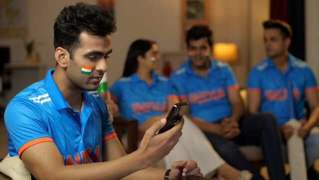 Cheerful Indian man looking at his smartphone - watching online live cricket match on app  cricket match. Indian friends chilling and watching cricket match at home - World Cup  Indian cricket fan ...