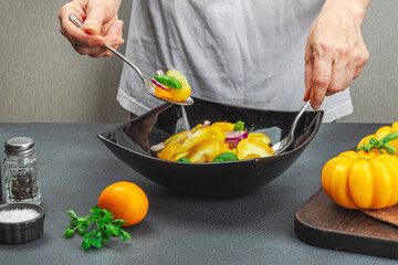 A woman is preparing a tomato salad. Ripe vegetables, herbs, aromatic spices, olive oil