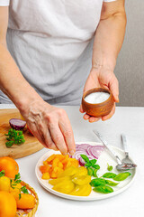 A woman is preparing a tomato salad. Ripe vegetables, herbs, aromatic spices, olive oil