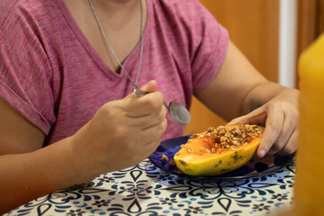 pessoa comendo mamão com granola