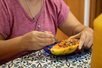 pessoa comendo mamão com granola