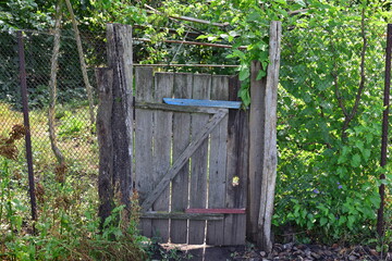 Old broken wooden gate in the garden, devastated countryside