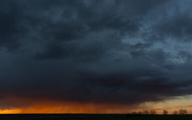 Fototapeta na wymiar Landscape at sunset. A thunderstorm is approaching the village. Tragic gloomy sky. Panorama.