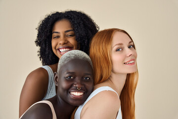 Happy cool pretty fashion gen z girls in underwear looking at camera, beauty portrait. Three smiling diverse young women, multicultural ladies models faces bonding isolated on beige background.