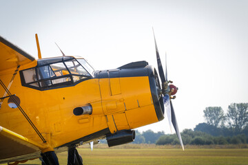 Nose of an old yellow-painted airplane with cockpit and propeller