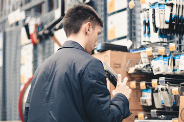 A young man inspects goods in a store.