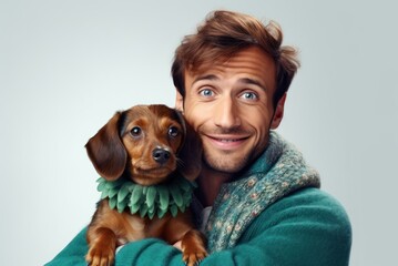 white man in warm, cozy green sweater hugging his beloved purebred Dachshund dog. Joyfully smiling. Happy owner. Cozy and atmospheric photo. On white background with copy space. Together with friend.