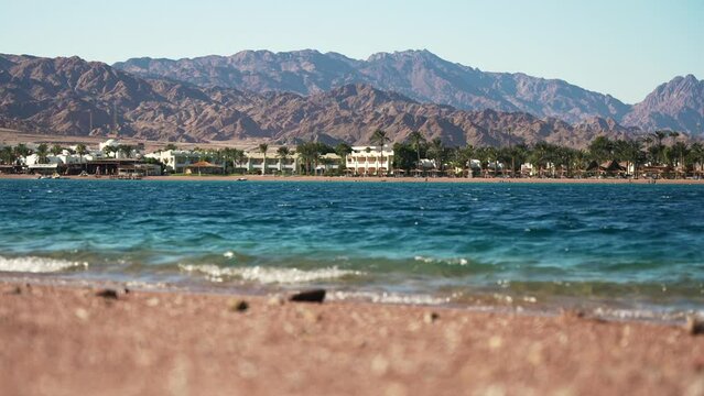Low angle view of the Dahab city coast. Blue lagoon waves in the foreground and mountains in the background