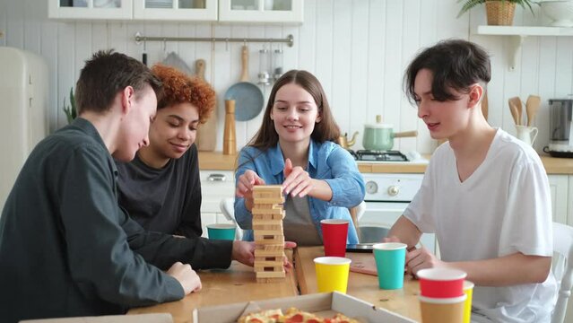 Home party. Friends spending time together playing in board game crash wooden tower at home. Happy diverse group having fun together indoor. Mixed race young buddies best friends enjoying weekend