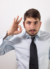 portrait d'un jeune homme d'affaires, ou employé de bureau qui fait un signe avec sa main pour montrer que tout va bien. Signe de réussite dans sa carrière