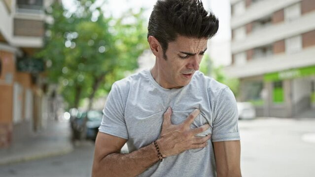 Young hispanic man suffering heart pain at street