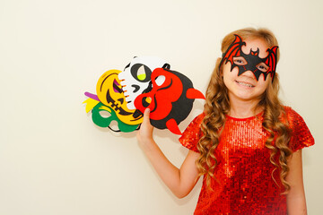 Halloween. Child in Halloween carnival mask. The child made handmade felt masks for Halloween. Kid in a bat costume. Girl prepared for Halloween celebration. Bat, pumpkin, witch, skull and devil masks