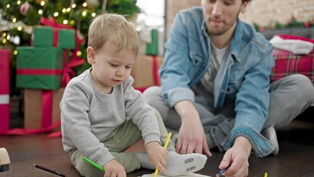 Father and son celebrating christmas drawing on notebook at home