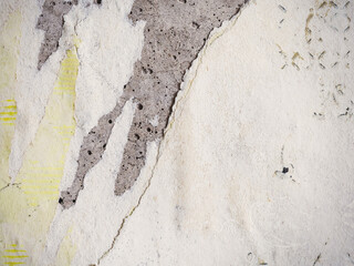 Fototapeta premium Torn old faded paper wallpaper with a retro pattern. Tattered scraps of paper on a concrete wall. Vintage texture for background and design. Closeup view with copy space.