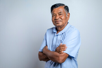 Portrait Asian elderly man. Smiling old man with arms crossed looking at camera isolated on gray...