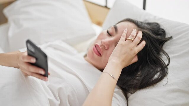 Young beautiful hispanic woman finishing to use smartphone to sleep at bedroom