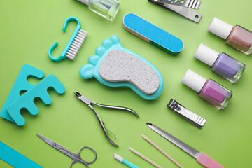 Set of pedicure tools on light green background, flat lay
