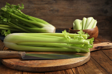 Fresh green celery bunches and knife on wooden table