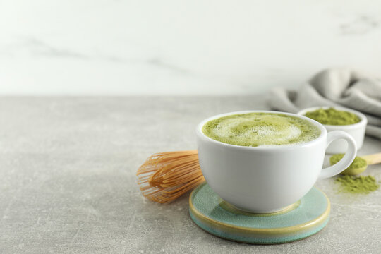 Cup of fresh matcha latte on light grey table. Space for text