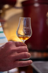 Tasting of cognac spirit aged in old French oak barrels in cellar in distillery in Cognac white...