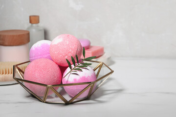 Beautiful aromatic bath bombs and green twig on white marble table, space for text