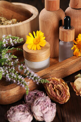 Jar, bottles of essential oils and different herbs on wooden table