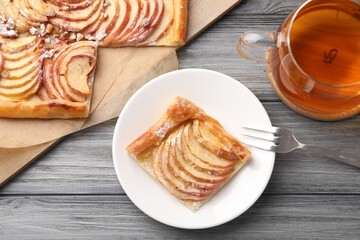 Tasty apple pie served with tea on grey wooden table, flat lay
