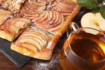 Freshly baked apple pie served with tea on wooden table, closeup
